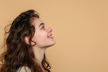 Profile side view portrait of attractive cheerful girl demonstrating copy space isolated on beige background