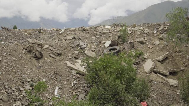 A pile of construction waste. Concrete rubble, old tires and plastic debris. Illegal dumping of construction waste and environmental pollution on a mountain.