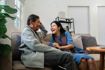 Older couples sit and chat and head over each other relaxed and happy on sofa at home on weekday in...