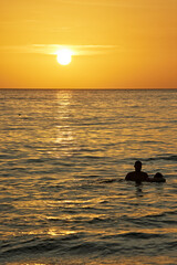 People swim in the sea against the backdrop of sunset