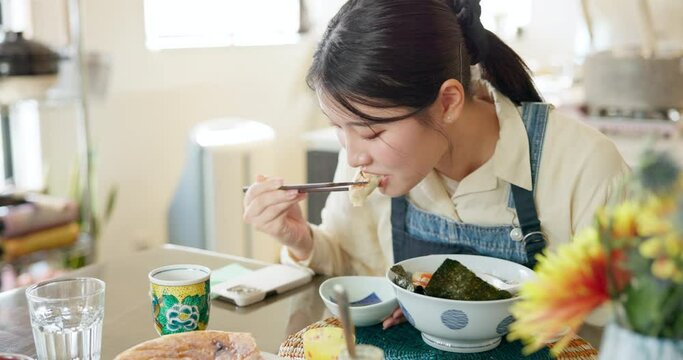 Japanese woman in restaurant, eating gyoza and food for lunch at dinner table. Chopsticks, dumpling and a young hungry person, customer or girl enjoying a healthy meal or traditional cuisine in bowl