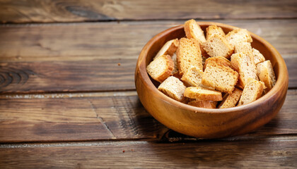 croutons in a wooden bowl on a wooden background/plate with dried bread on a wooden background