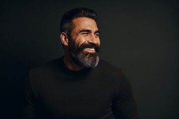 Portrait of a handsome bearded man in a black sweater on a dark background.