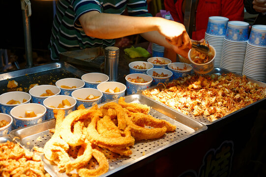 A stall vendor selling crispy fried seafood in paper cups, one of local people's favorite street-foods, in Flower Night Market, where many traditional snacks can be savored, in Tainan, Taiwan, Asia