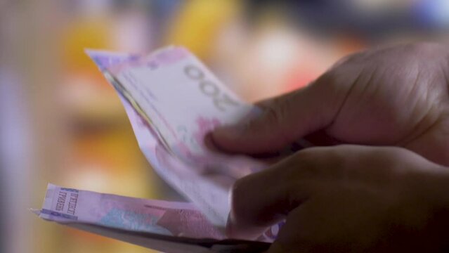 Person holds and counts hryvnas. Blurred background. Social aid concept