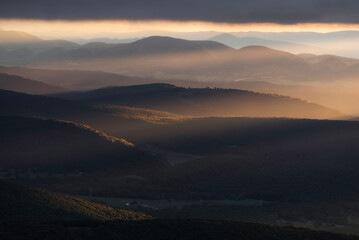 Rays of light fill the valleys of West Virginia during an overcast Autumn sunrise in the Appalachian Mountains. - obrazy, fototapety, plakaty