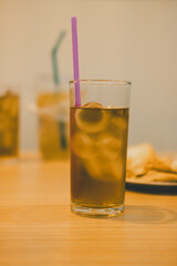 Organic Iced tea with ice cubes and pink straw at table dinner