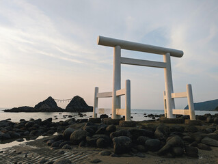 A serene and peaceful scene of a beach during low tide, with a prominent white torii gate on the...