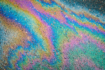 Rainbow gasoline oil spill on the pavement as a texture or background.