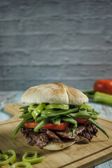 Chacarero with chili, green beans, meat, and tomato on a cutting board on a wooden table. Copy space, Vertical. Typical food and drink of Chile