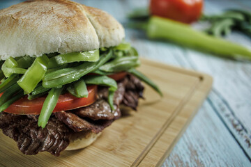 Chacarero Close-up detail with chili, green beans, meat, and tomato on a cutting board on a wooden table. Copy space. Typical food and drink of Chile