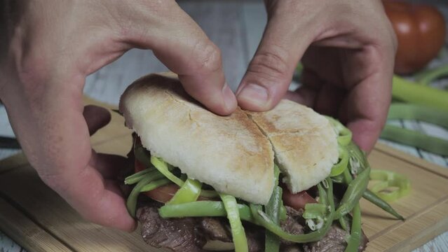Chacarero front video showing expert hands cutting with a knife on a wooden cutting board. Cross-sectional view of the sandwich. Typical Chilean food and drink