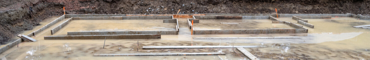 Under construction, residential house foundation dug out and framing started, flooded with...