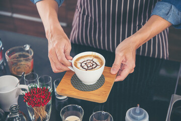 Coffee barista pour espresso shot and make latte art hot coffee cup. Cappuccino with milk in italian coffee shop cafe. Close up hands of barista make brown latte art for customer cafeteria. - obrazy, fototapety, plakaty