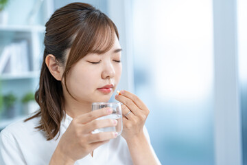 自宅で薬を飲む日本人女性