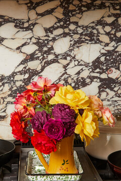 Garden roses in yellow painted vase in kitchen in front of marble background