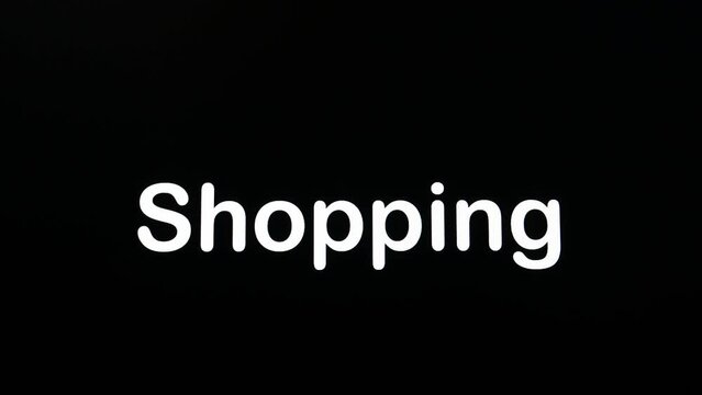 Typing on the screen with a flashing paragraph forming the word Shopping, in white on a black background