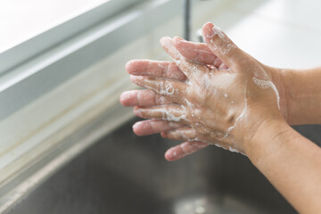 Close up woman hand washing under running water in the kitchen.Hygiene and cleaning hands.Image...