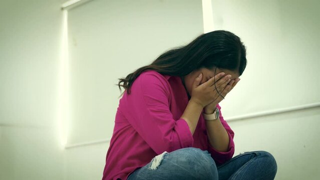Depressed Asian woman massaging her head trying to relieve stress