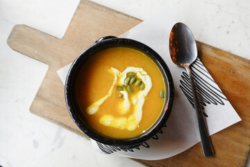 Delicious pumpkin soup in bowl on wooden table,