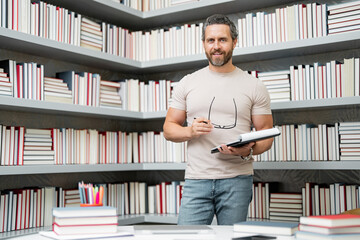 Portrait of teacher in library classroom. Handsome teacher in university library. Teachers Day....