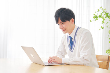 リビングでノートパソコンを使う男子高校生