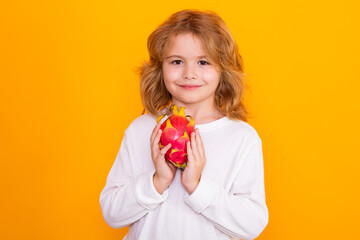 Kid hold dragon fruit in studio. Studio portrait of cute child with dragon fruit isolated on yellow background, copy space.