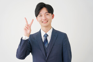 ピースサインをする若いビジネスマン　白背景