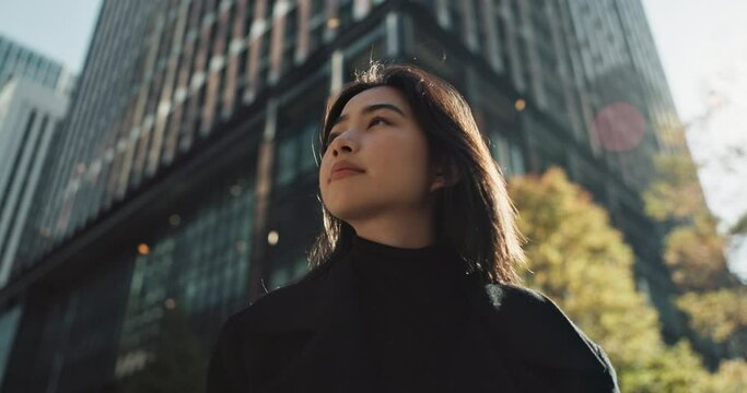 Japanese woman, thinking and positive in city for work and relax wellness in outdoor environment. Young person, peace and professional career in tokyo by corporate buildings and travel in urban town