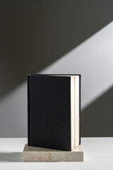 Black notepad in sunlight against gray background