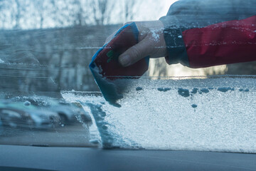 Ein Mann kratzt die gefrorene Scheibe eines Auto frei