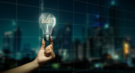 Double Exposure of Businessman holding glowing light bulb with the word idea on night city...