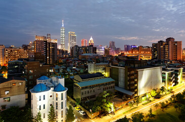 Naklejka premium Night skyline of Downtown Taipei, vibrant capital city of Taiwan, with the famous landmark 101 Tower standing among high-rise buildings in Xinyi Financial District and city lights dazzling in the dark