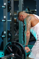 Fototapeta na wymiar Man bodybuilder in white shirt training in a gym