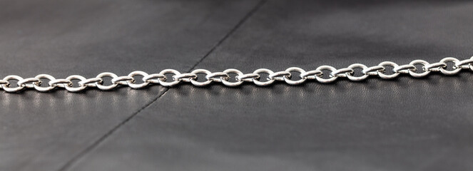 Silver chain on a black leather background