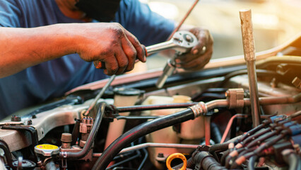 Mechanic using wrench while working on car engine at garage workshop, Car auto services and...