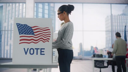 Young African American Woman Filling Out a Ballot Next to a Voting Booth on the Day of Elections in the United States. Diverse Men and Women Voting for Presidential Candidates in a Polling Station