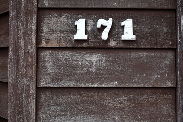 Numbers 171 on wooden siding, white on brown.