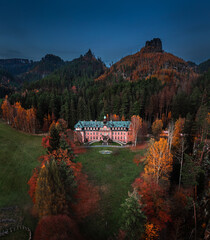 Jetrichovice, Czech Republic - Aerial view of beautiful pink mansion near Jetrichovice at dusk on an autumn afternoon with Mariina vyhlidka viewpoint and blue sky at background in Bohemian Switzerland