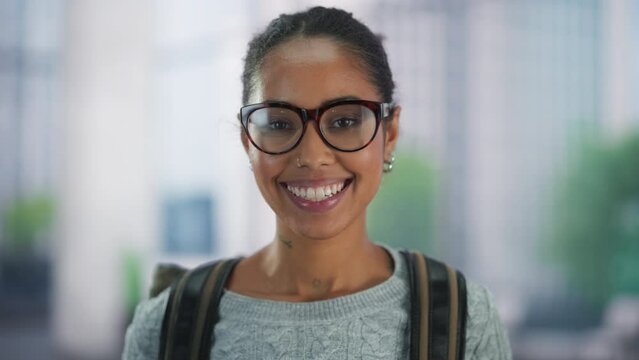 Beautiful African Female Student Standing in a Modern School Hall. Close Up Portrait of a Young Happy Successful Black Woman Looking at Camera, Posing and Smiling. Girl Wearing Stylish Glasses