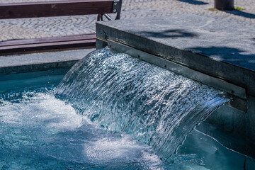 Water cascading from marble enclosure into fountain pool in popular park in Bratislava, Slovakia.