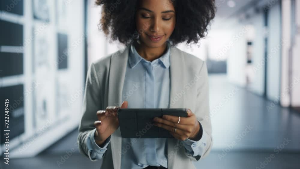 Poster portrait of a cheerful female project manager smiling while checking information on a tablet compute