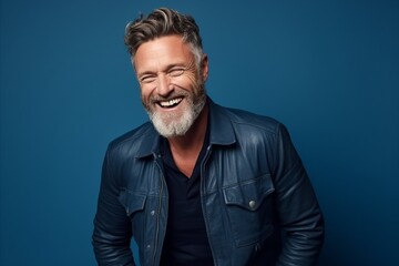 Portrait of a handsome mature man smiling against blue background. Men's beauty, fashion.