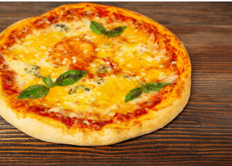 Cheese pizza with basil on a wooden background, close-up