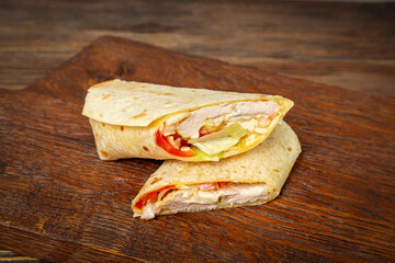 Shawarma, doner with chicken, cabbage and tomato on wooden background