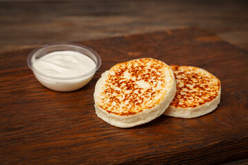 Curd cheesecakes with sour cream on a wooden background