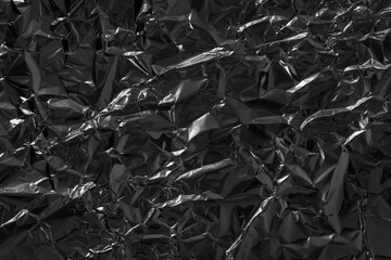 Shiny black foil texture background, pattern of wrapping paper with crumpled and wavy.