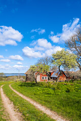 Sunny spring day with a dirt road by a old farm