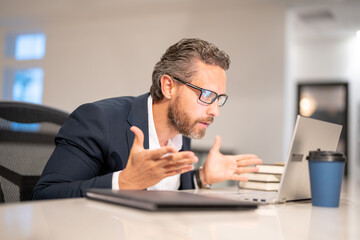 Fototapeta premium Middle aged businessman working with laptop in office. Surprised business man using laptop. Surprised man using laptop at office workplace. Ceo manager office worker business people working at office.