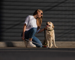 A blind woman walks her guide dog on the street. Girl hugging a labrador. 